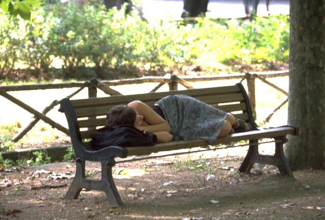 Estudiante dormida sobre un banco de un parque